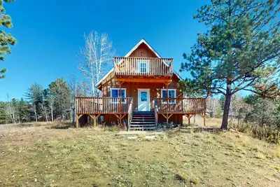 Image de A-frame home lined by trees with wood stove, balcony, children's items, & W/D