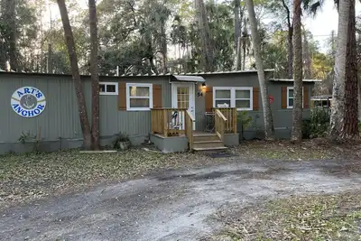 Image de Step into this cozy 2-bedroom cabin nestled in the tranquil woods. The main living area offers comfy seating, including a pull-out futon for additional sleeping space. An efficiency kitchen awaits your culinary adventures, equipped with essentials fo