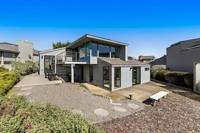 Image de Golf course-adjacent home with an ocean view, deck, patio, & fire table
