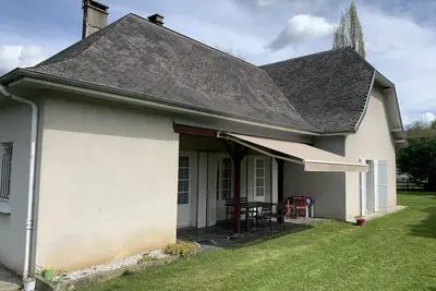 Image de Maison avec terrasse et jardin au pied de la montagne.