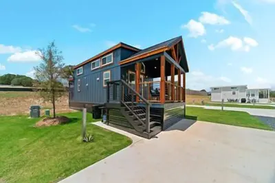 Image de Texas Farmhouse-Style Blue Tiny Home Features Dual Porches, Multi-Level Sleeping Areas, and Full Kit