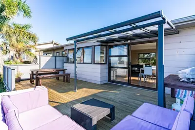 Image de All Decked Out - Modern holiday home with multiple decks including a covered outdoor entertaining space with open fireplace and plastic blinds. Close to shops, cafe, golf course, estuary and Mangawhai Activity Zone. Pet Friendly.