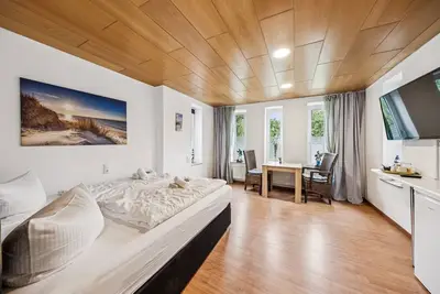 Image de Cozy double room, seating area, flat-screen Tv, and modern bathroom with shower. Ideal for couples and short stays – enjoy a relaxed atmosphere with warm wood accents and coastal charm.