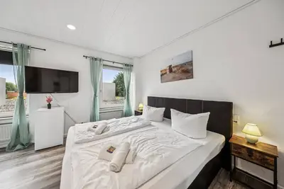 Image de Cozy double room, flat-screen Tv, and modern bathroom with shower. Ideal for couples and short stays – enjoy a relaxed atmosphere with warm wood accents and coastal charm.