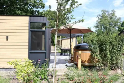 Image de osendael: Stylish 4-person home with 2 bedrooms, each with en-suite bathrooms—one with a whirlpool and the other with a shower and sunshower—a hot tub, partially covered outdoor terrace, and modern kitchen. Enjoy luxury in the Veluwe!
