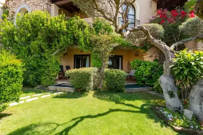 Image de Villa 2000-Rokkaria is a charming terraced house within an elegant condominium in the center of Villasimius. The property stands out for its Moorish-style architecture, surrounded by lush vegetation, and enjoys a prime location between the sea and the tow