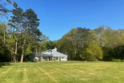 Image de Maison de charme à travers un jardin paysager proche de la mer. .