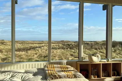 Image de Vue sur la mer dans une maison de vacances nostalgique des années 60 au bord d'une dune
