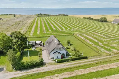 Image de Maison idyllique avec toit de chaume et vue sur la mer