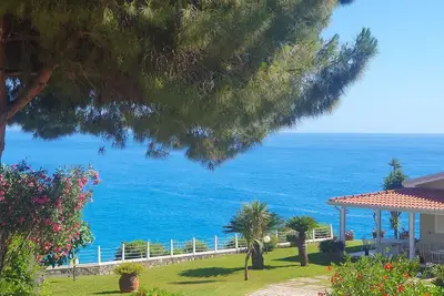 Image de A beachfront cottage perched on a cliff, nestled in the lush greenery of the garden