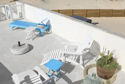 Image de Maison située en bord de mer, sur une longue plage de sable blanc.