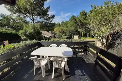 Maison moderne entre forêt et océan, avec jardin et terrasse.