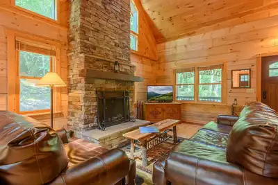 Image de Cabine privée Creekside avec bain à remous, foyer, cheminée en pierre, mobilier en cuir, climatisation centrale