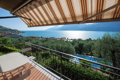 balcon magnifique sur le lac avec une belle piscine et le jardin au milieu de palmiers et d'oliviers