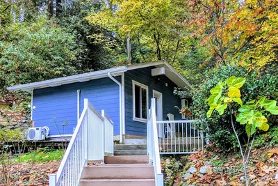 Image de Petite maison privée récemment rénovée entourée d'arbres