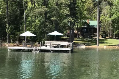 Image de Grand chalet en bois rond: ciel bleu, herbe verte et vie sur le lac