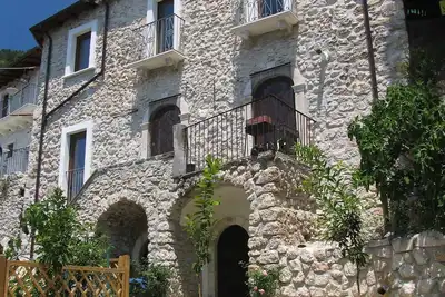 Image de Maison italienne traditionnelle en pierre avec balcons, jardin fruitier et toit-terrasse avec vues.