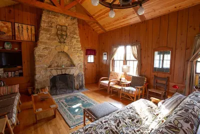 Image de Cabine \/ chalet classique avec grande véranda, cheminée en pierre, murs de pin noueux