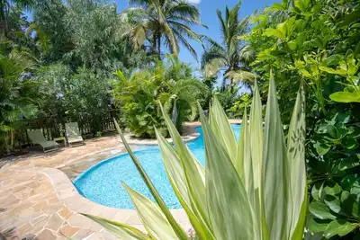Image de Bungalow de charme Hibiscus en bois exotique, piscine dans un jardin tropical.