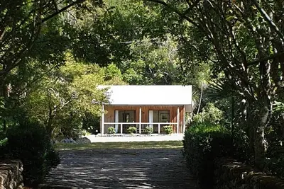 Cabane rustique et grand bloc de cuisine niché dans un jardin indigène.