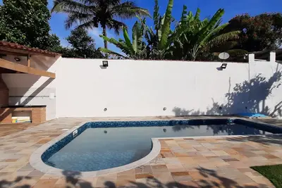 Image de Maison de plage avec piscine et barbecue.