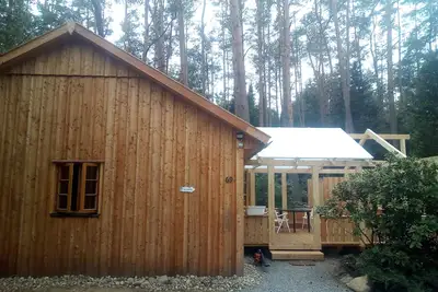 Image de La maison de vacances \"Ortheide 69\" est située dans un village forestier avec de grands arbres.