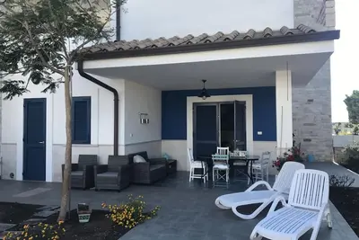 Image de villa de prestige sur la mer avec jardin, parking et terrasse ensoleillée.