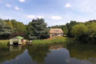 Image de Luxury Lakeside Home Dans un vaste terrain avec des bateaux, des canoës et un court de tennis.
