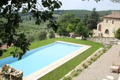 Image de Villa Arnica A: Une ancienne ferme toscane caractéristique et accueillante entourée de vignes et d'oliviers.
