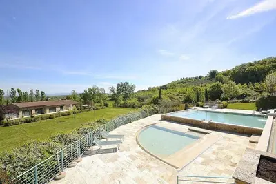 Image de Villa Fontanile D: Un appartement élégant et accueillant qui fait partie d'une villa entourée de verdure.