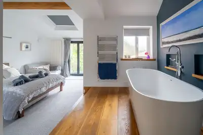 Image de Un chalet contemporain de quatre chambres situé à quelques pas de la plage de Holme. La maison a un jardin magique de presque un acre avec des zones de pelouse, un «bois secret» et une maison de théâtre pour enfants. Le logement est élégant.