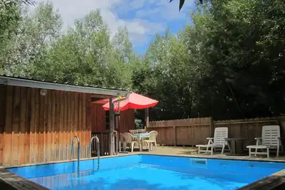 Image de Lodge en bois avec terrasse et piscine dans un cadre verdoyant