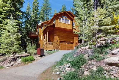Image de Superbe maison familiale entourée d'arbres avec une terrasse meublée et un barbecue
