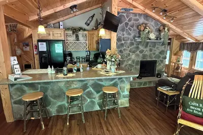 Image de Belle cabane 2 chambres avec un mur de fenêtres donnant sur la terrasse et le ruisseau.
