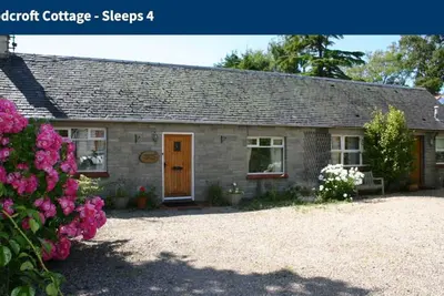 Image de Woodcroft Holiday Cottage à Ayr est situé dans le jardin avec pelouse, face à l'ouest