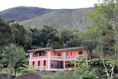 Image de Casa Tico tico das Araras surrounded by mountains in a forest reserve.