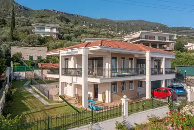 εξοχική ισόγεια κατοικία σε κήπο με γκαζόν με θέα θάλασσα και καταπράσινο λόφο