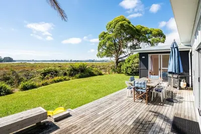 Image de Wintle93 - Stunning Views await you from the living areas and sunny deck of this traditional kiwi bach which has been tastefully modernised and is within a few minutes walk to both surf beach and estuary beaches. Pet friendly and Free wifi included!