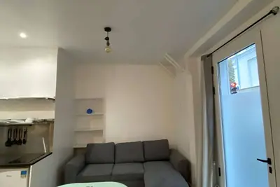Image de L'appartement dispose d'un lit, d'un canapé-lit et d'une cuisine avec un réfrigérateur