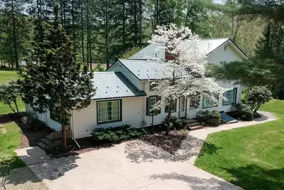 Image de Creek side house with fireplace and concrete driveway.