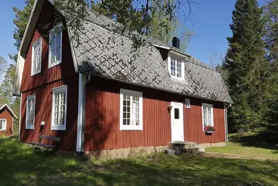 Typical red and white holiday home surrounded by forest and lake