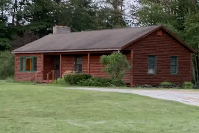 Image de Cabin is nestled near the Sugar River in a country setting next to a open field.