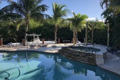 Tropical waterfront oasis with private dock, pool, waterfall spa, tiki huts.